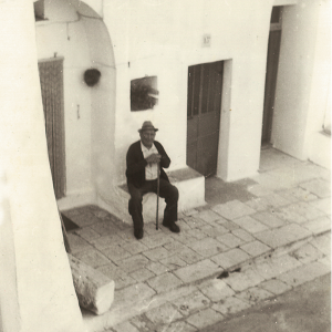 Foto in bianco e nero di un uomo anziano seduto all'ingresso del trullo