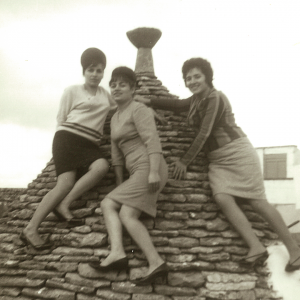 Foto in bianco e nero di tre ragazze sul cono di un trullo