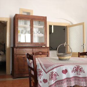 Foto della sala principale con il tavolo in primo piano e le porte delle due camere da letto ai lati della credenza in secondo piano