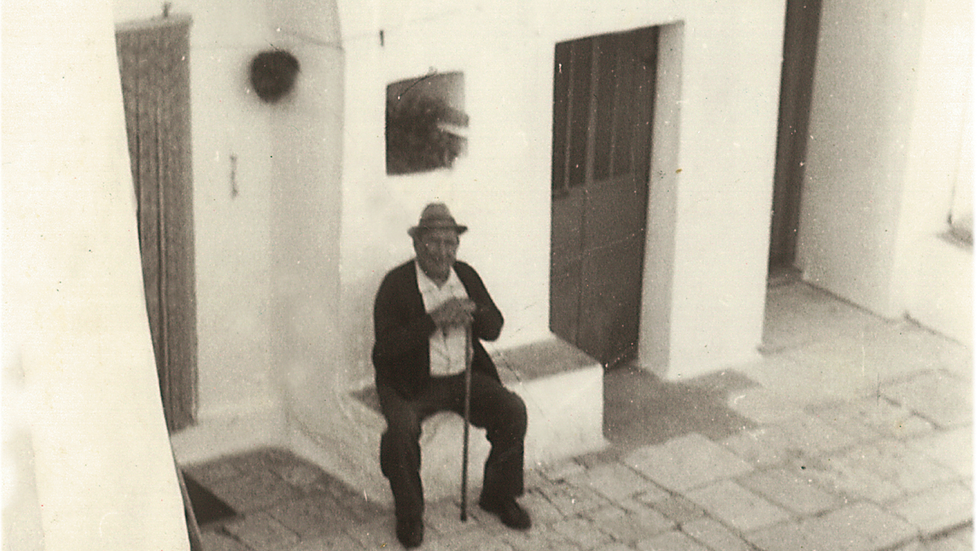 Foto in bianco e nero di un uomo anziano seduto all'ingresso del trullo